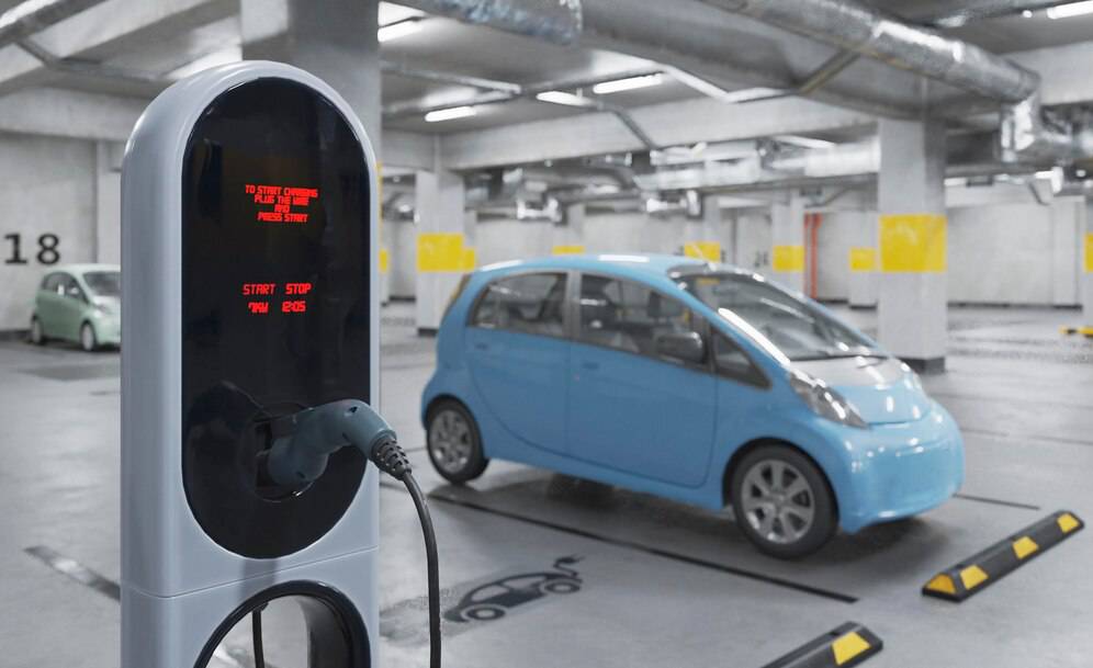 A modern electric vehicle charging station with a blue car parked nearby in a spacious underground parking garage.