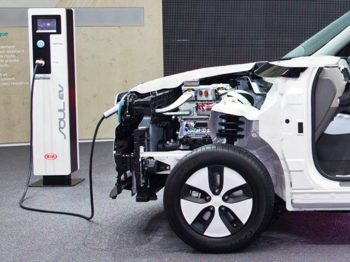 Kia Soul EV with its side cutaway revealing internal components, connected to a charging station.