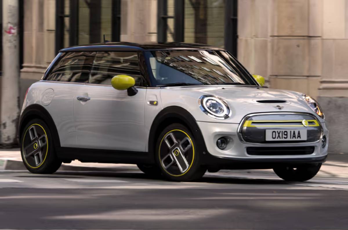 A sleek, white Mini Electric car with yellow accents, parked on a city street, showcasing modern design and eco-friendliness.