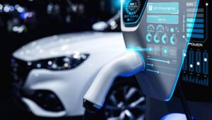 A close-up of an EV charging station displaying charging metrics, with a white electric vehicle blurred in the background.